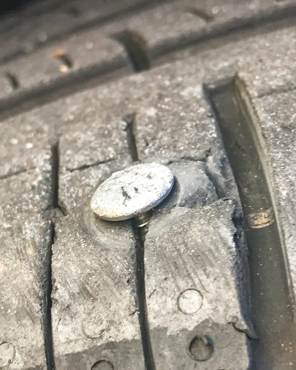 Cabeça de um prego cravado na banda de rodagem do pneu