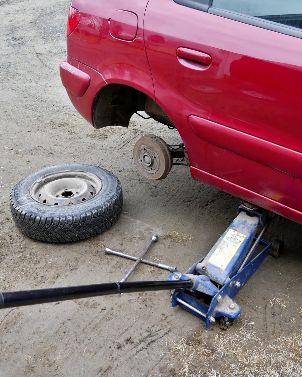 Carro erguido no macaco, com a roda fora e a chave de roda no chão